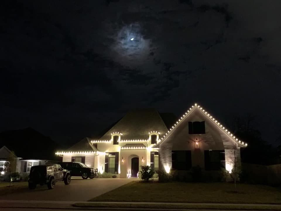 Home roofline outlined in warm white Christmas lights under a moonlit sky