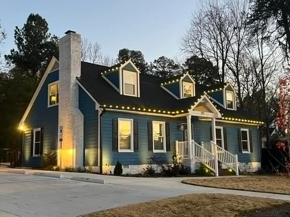 Blue cottage-style home with dormer and roofline Christmas lights